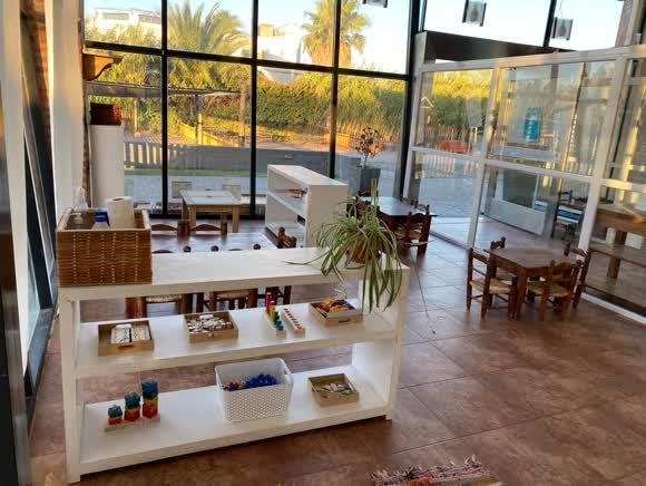 Sala del jardín con estantería de materiales y ventanal de piso a techo