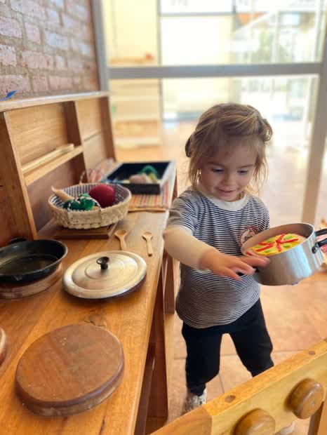 Nena jugando en la cocinita de madera de la sala