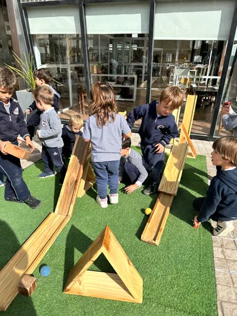 Chicos construyendo con bloques grandes de madera en el patio