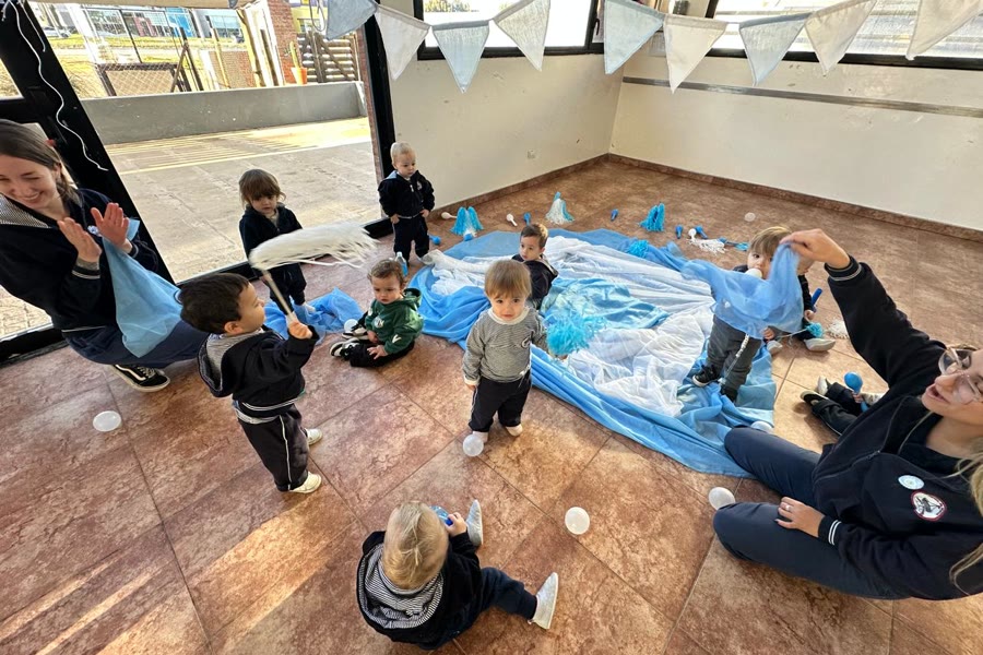 Chicos jugando sobre una lona azul en el patio cubierto del jardín