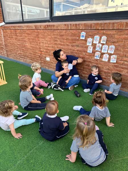 Ronda de chicos con una docente en el patio del jardín